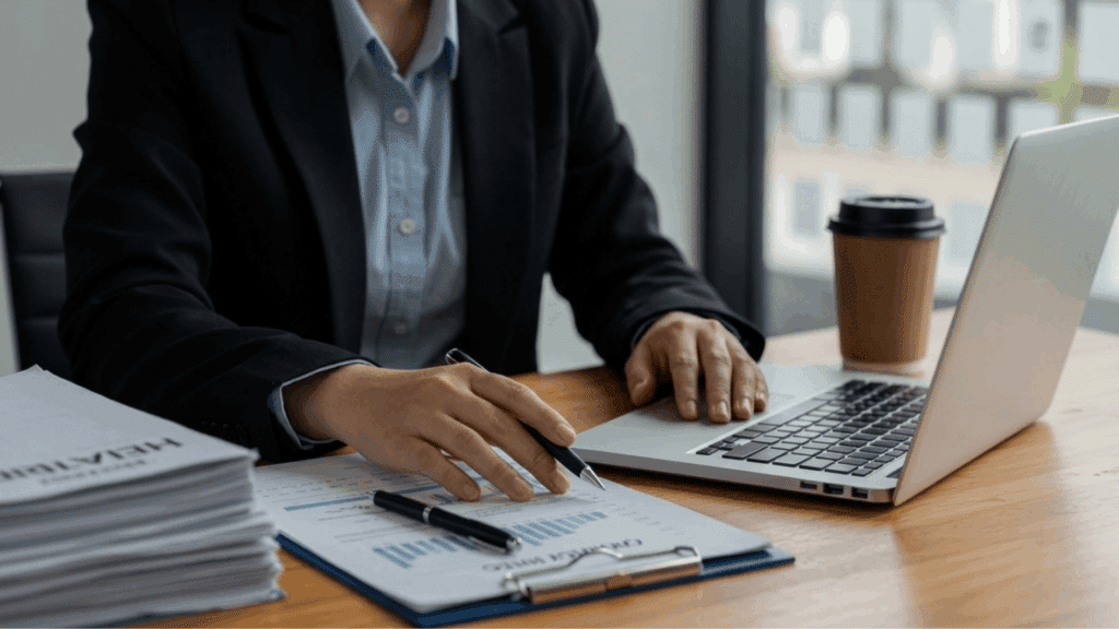 hr professional reviewing compliance checklist and documents at office desk with laptop and files