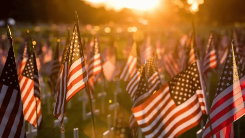 American flags placed on graves in a cemetery during sunset, symbolizing honor and remembrance for the fallen heroes