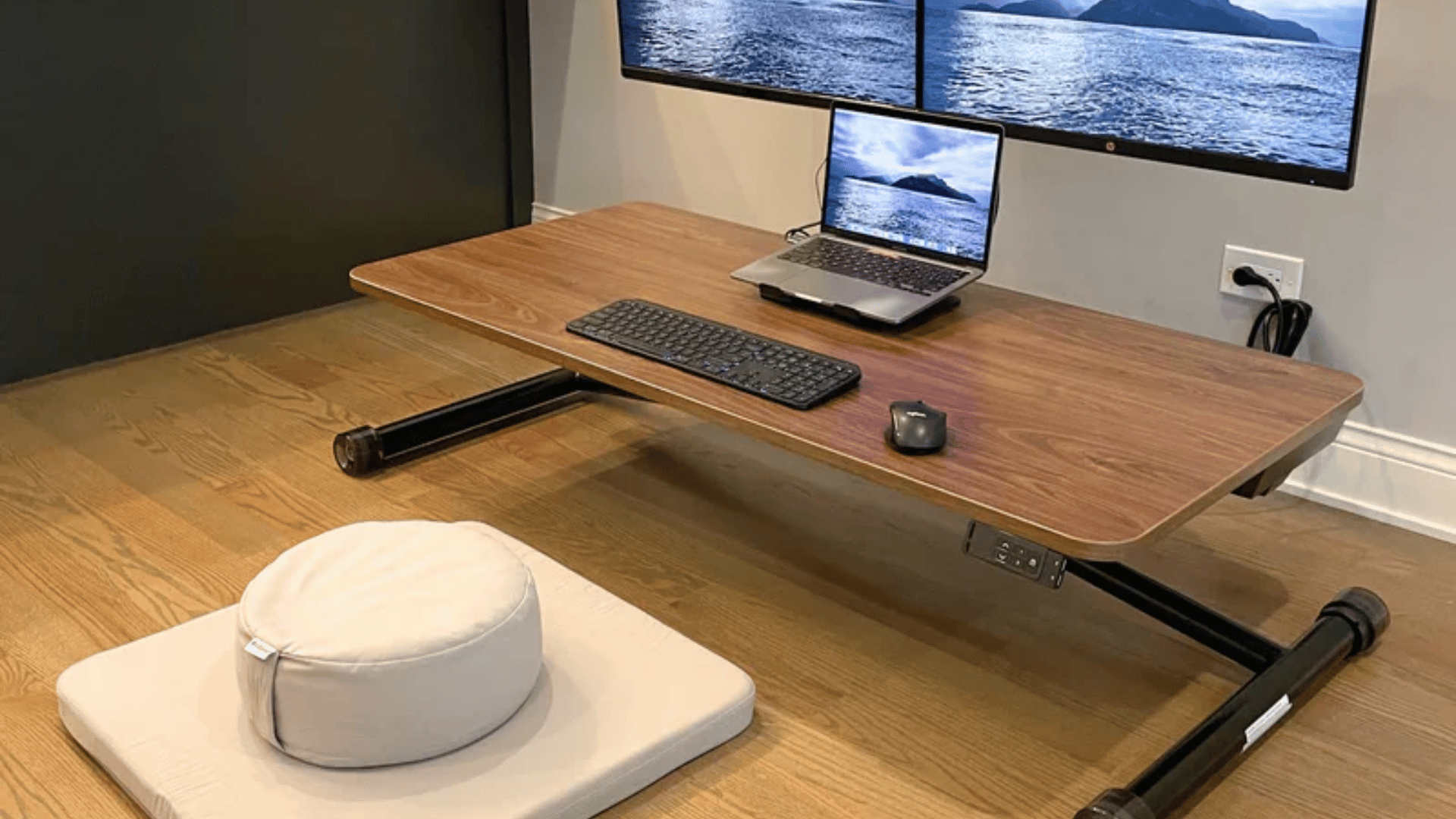 small foldable desk on the floor with laptop on top and cushion at side