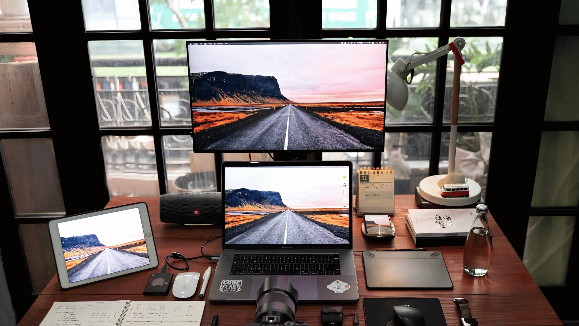 Creative remote work setup with dual monitors, tablet, camera, and desk accessories
