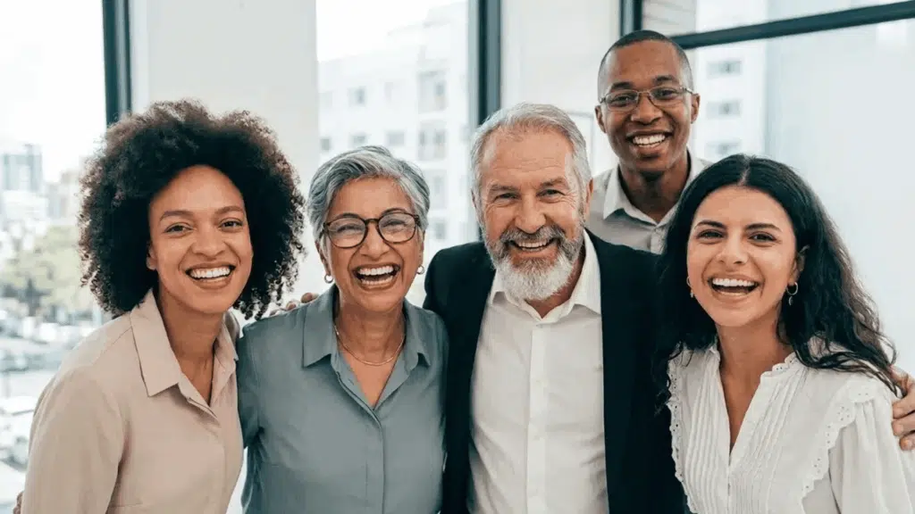 Diverse coworkers smiling together in an office after a successful team achievement and workplace appreciation moment.