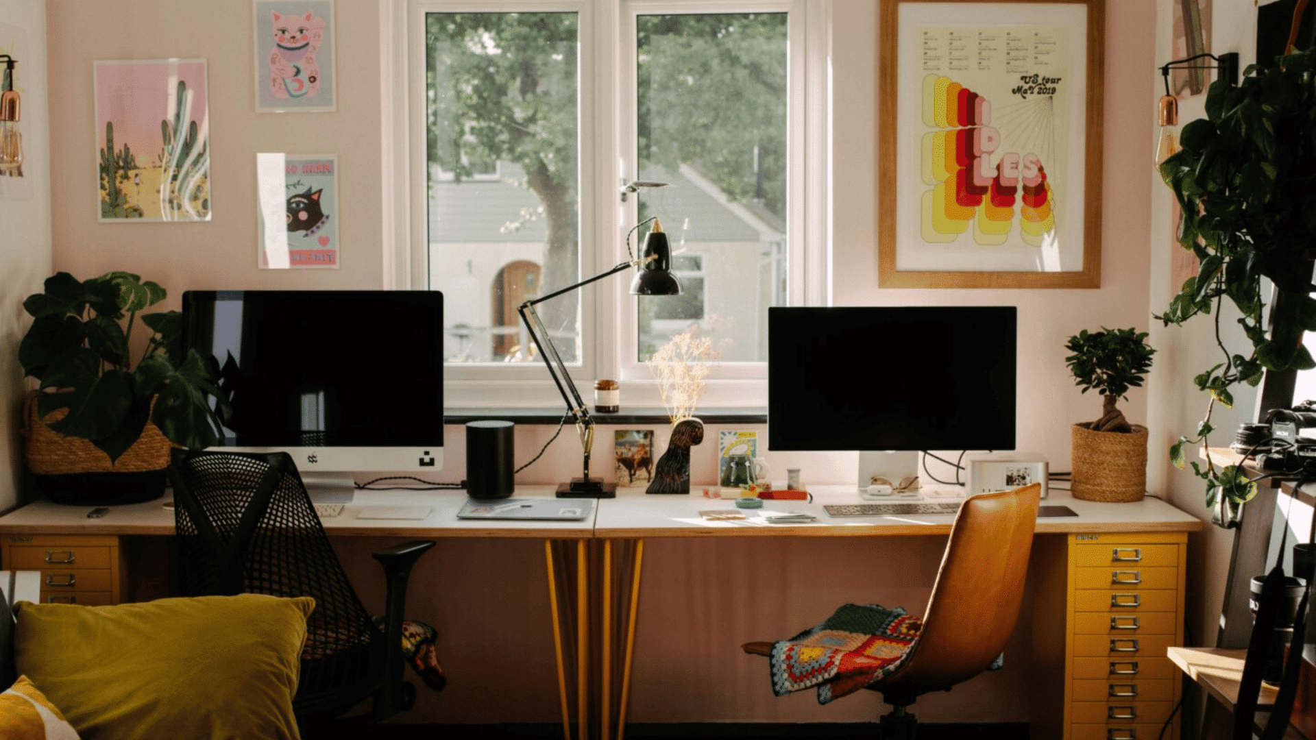 Two monitors on a long desk with window in middle