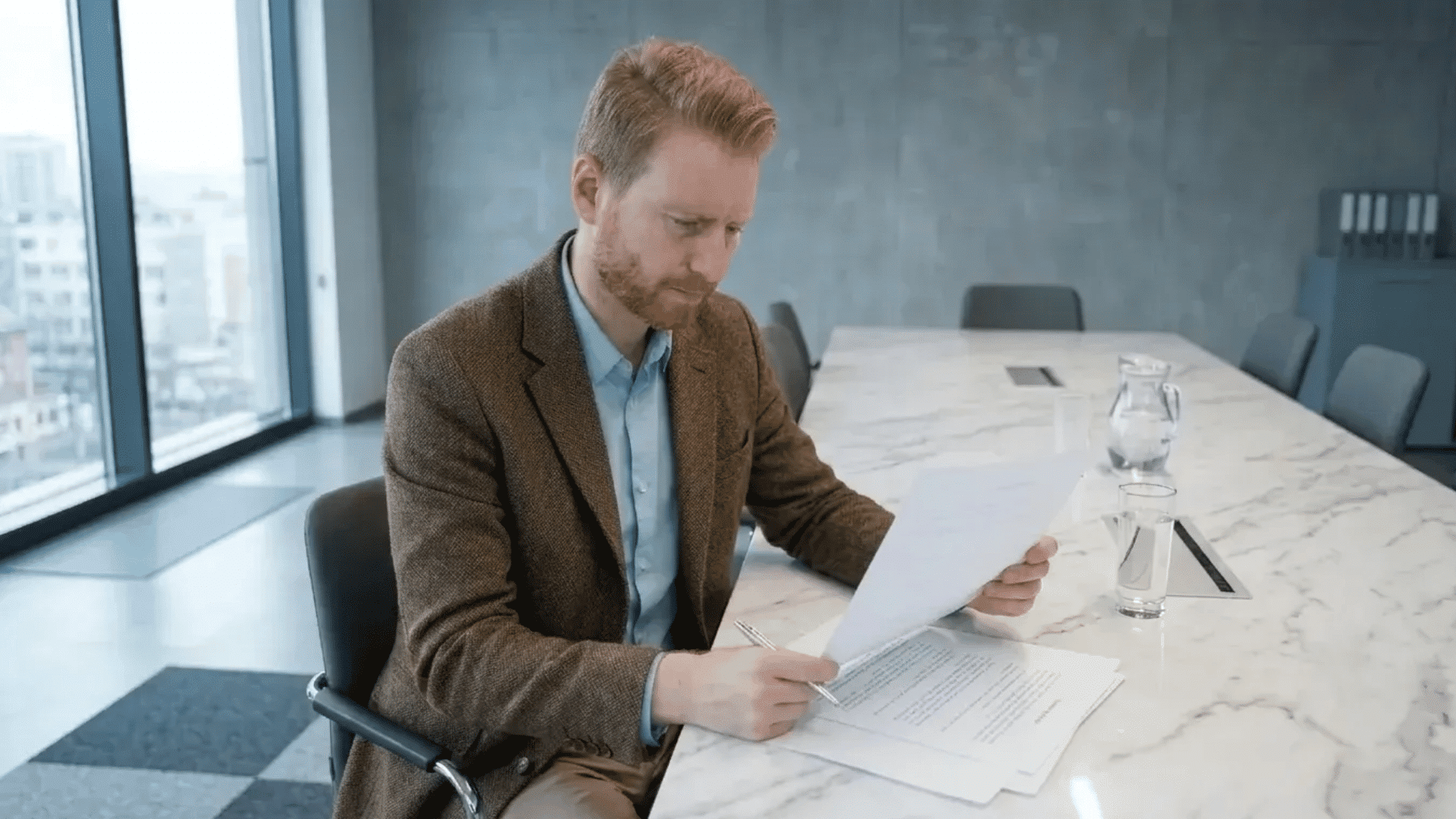 Employee reviewing workplace write-up documents alone in a modern office conference room with a serious and focused expression.