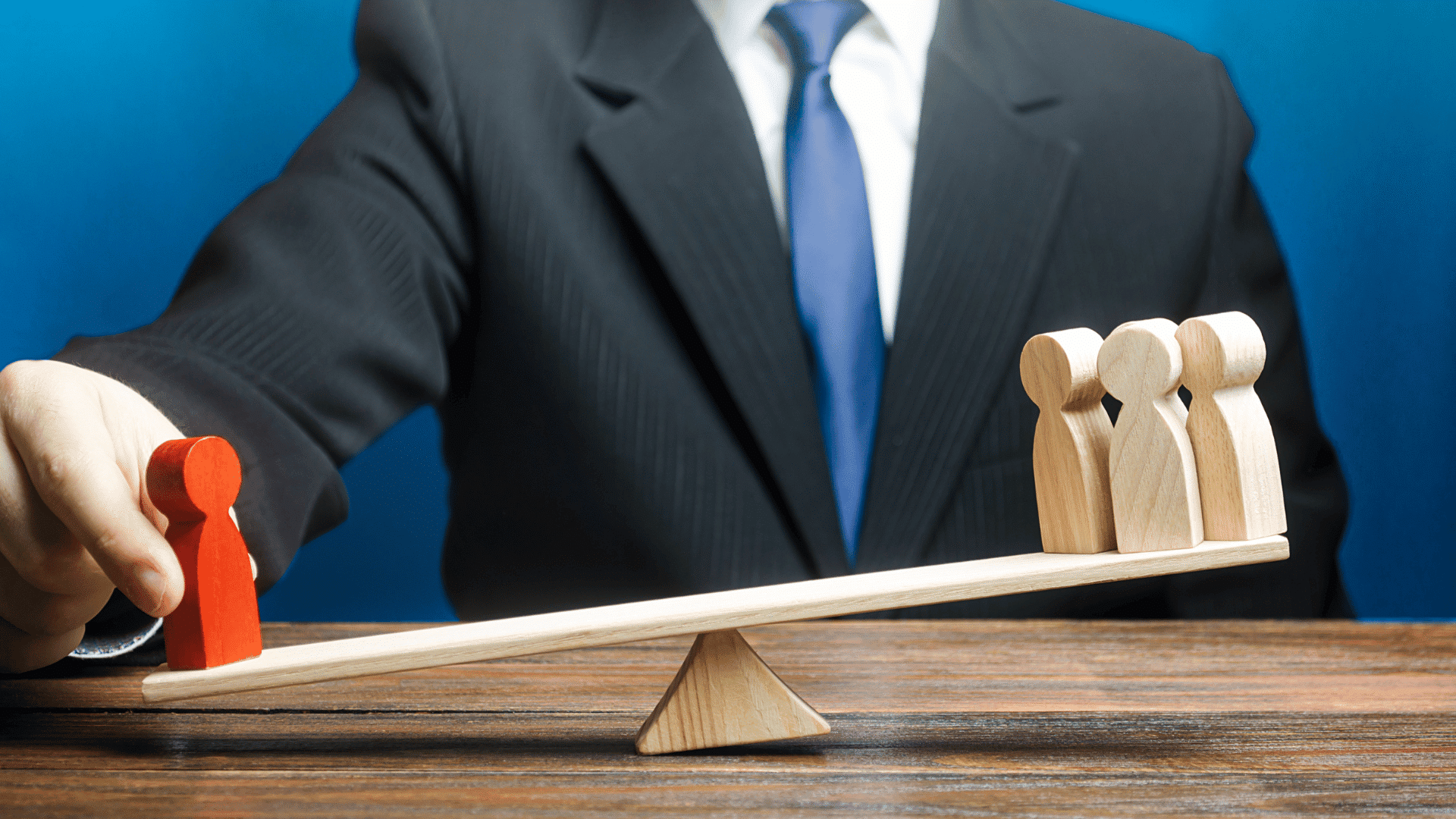 Businessman tipping a scale in favor of one wooden figure over three others
