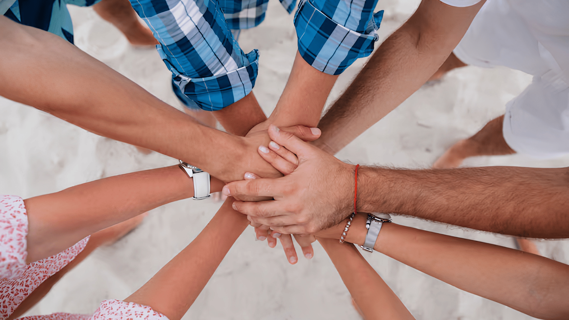 Diverse group of people stacking hands together in a show of teamwork and solidarity