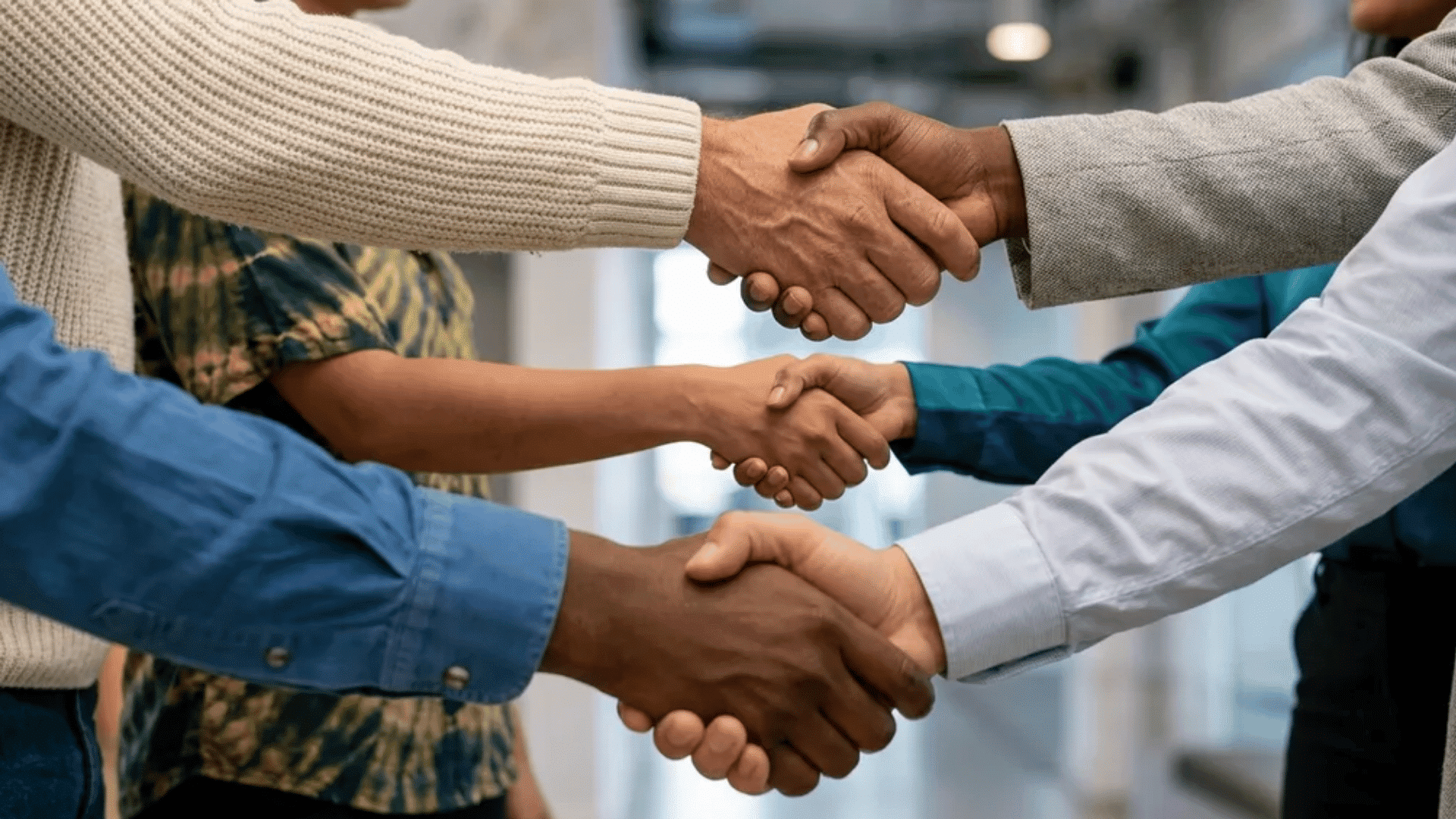 Multiple people shaking hands in a group, symbolizing cooperation and mutual respect.