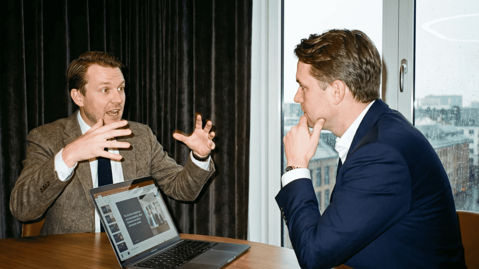 Two professionals discussing what is probation period during an office meeting with a laptop.