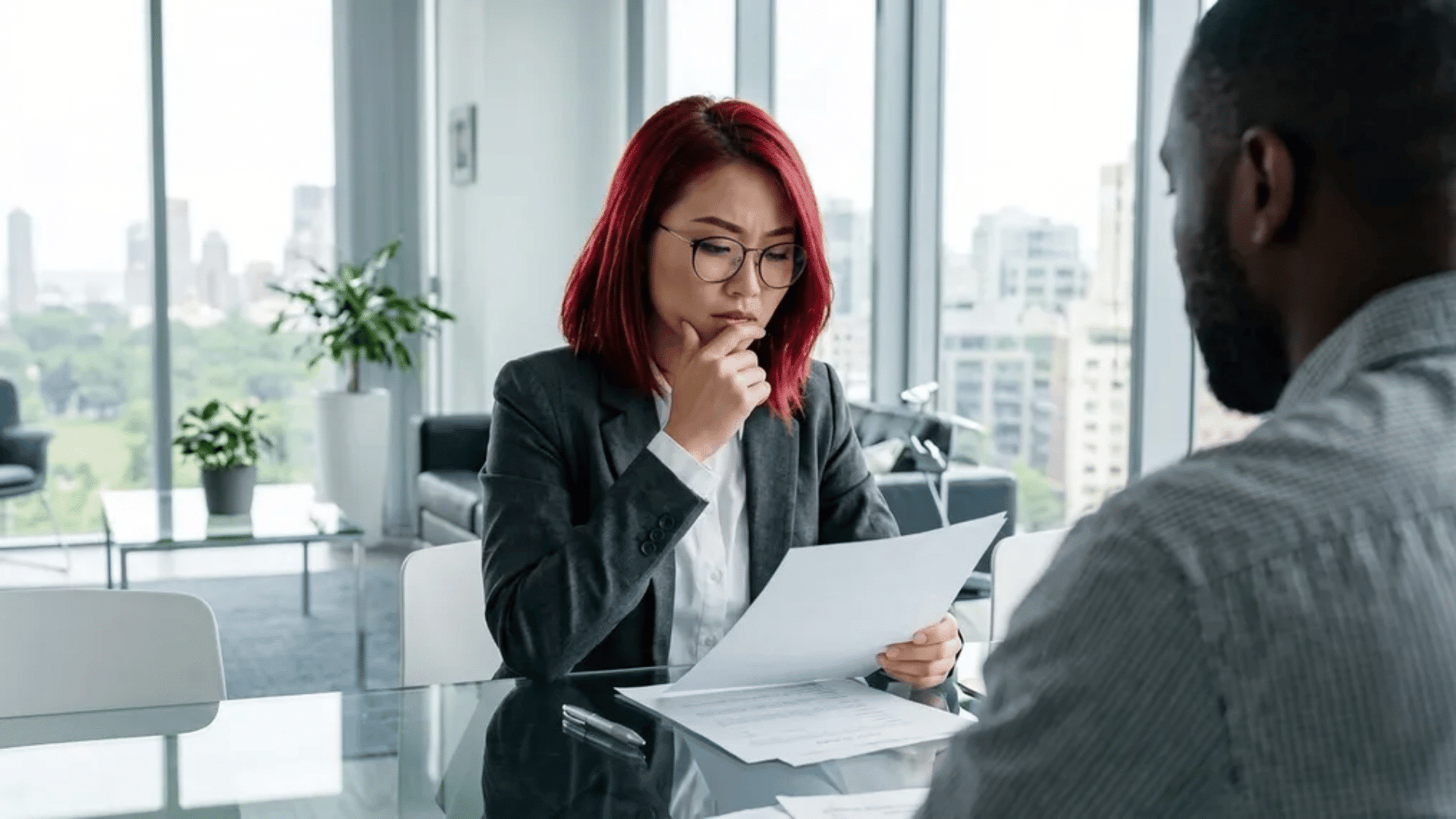 Woman in office receiving an employee write up form during a meeting seated across the table.