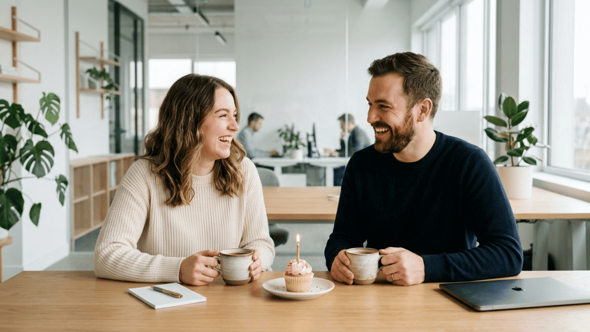 coworkers shaking hands beside flowers to celebrate a work anniversary in a bright office