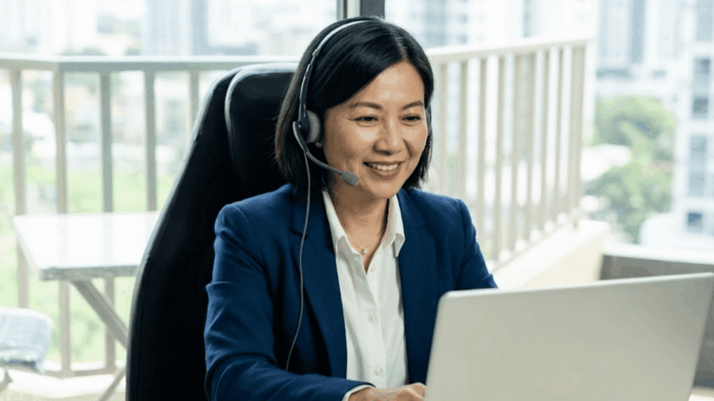 background check specialist wearing a headset while assisting clients from a laptop in a bright office