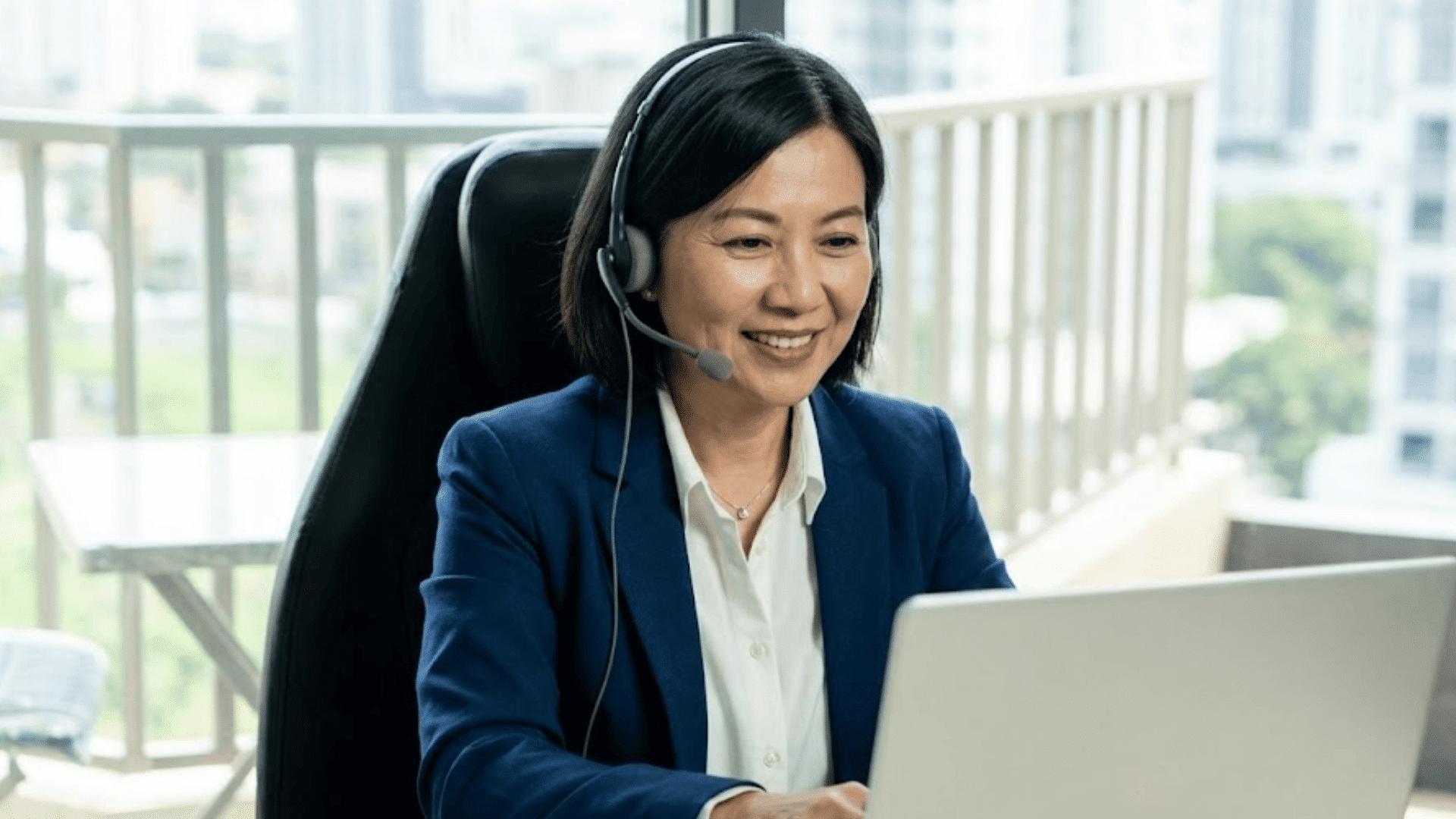 background check specialist wearing a headset while assisting clients from a laptop in a bright office