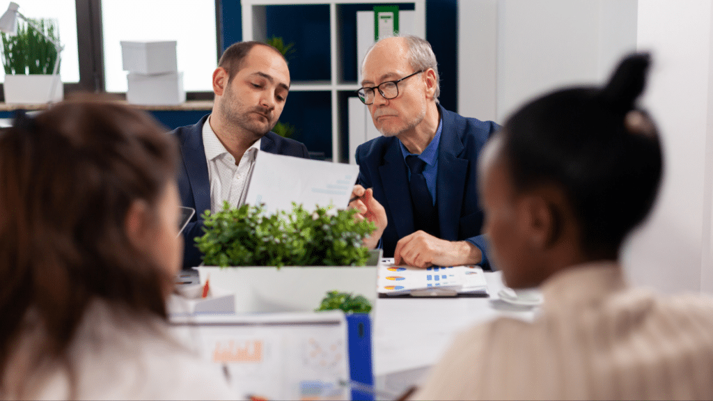 Managers reviewing documents during a workplace meeting, representing employment decisions involving political affiliation and discrimination.